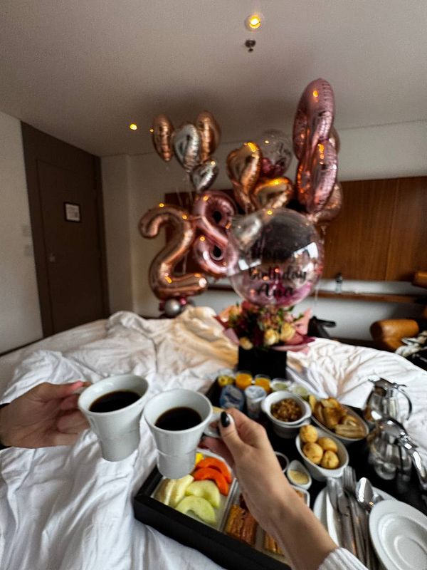 A cozy birthday breakfast surprise featuring coffee, food, and festive balloons.