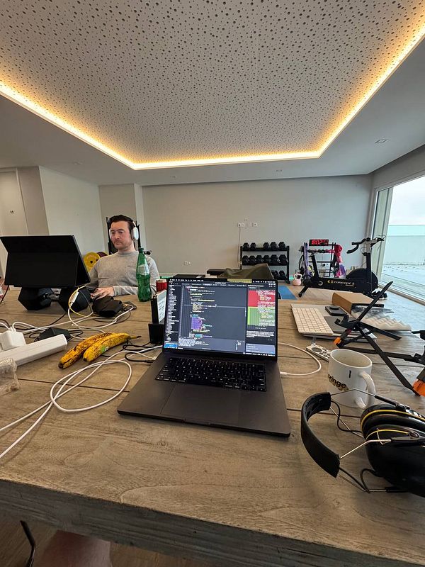 A coworking space featuring a laptop, a person working, and fitness equipment in a bright room.