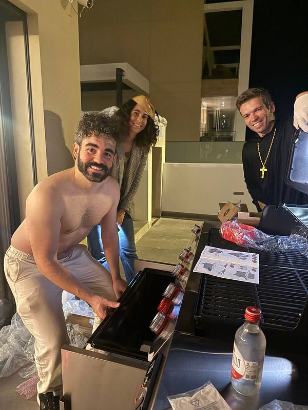 Three friends are preparing for a Halloween BBQ party outdoors.