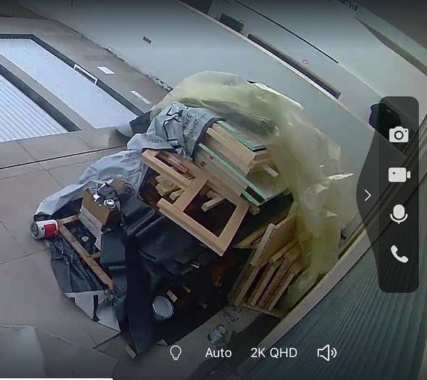 A pile of sauna wood and materials is seen in a garden, partially covered and exposed to the elements.