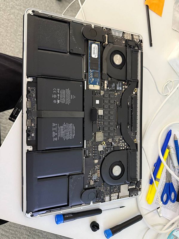 The image displays the internal components of an old MacBook with the hard drive and battery exposed.