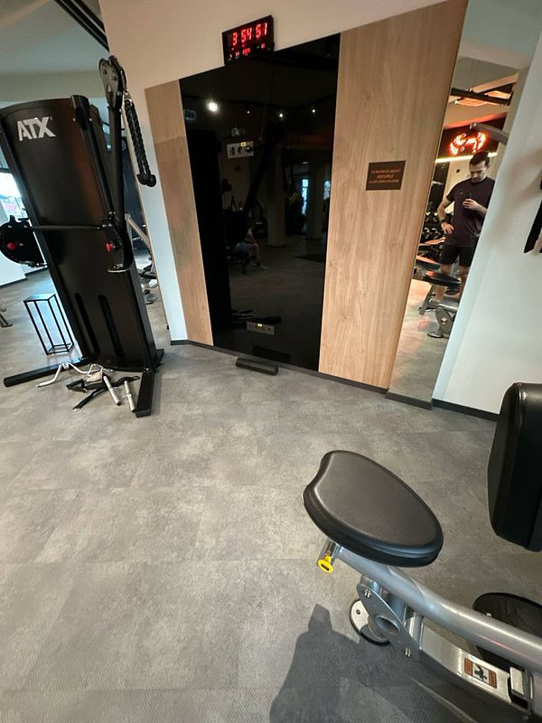 The image captures a gym interior featuring workout equipment and a digital timer.
