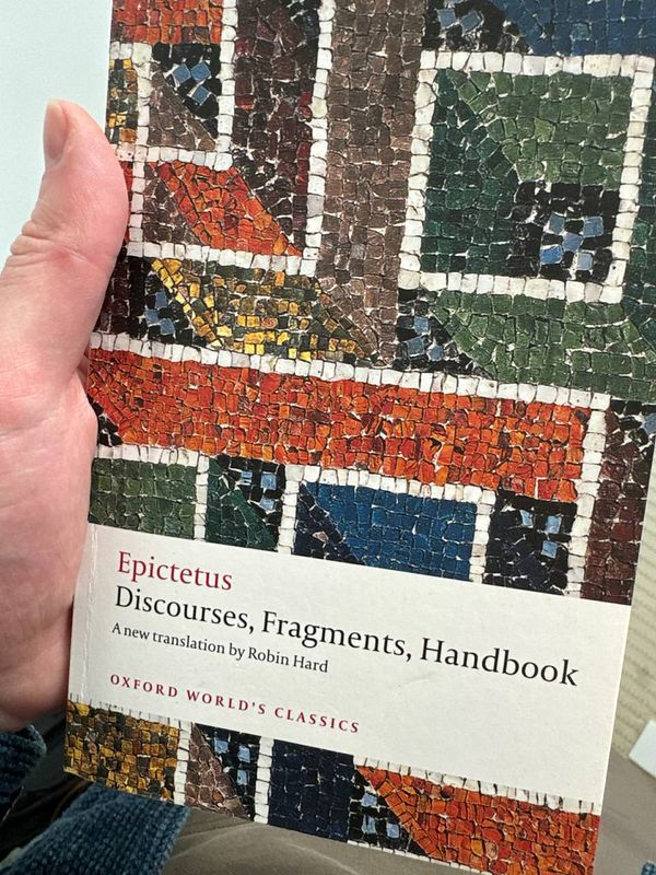 A person is holding a book titled 'Epictetus: Discourses, Fragments, Handbook'.