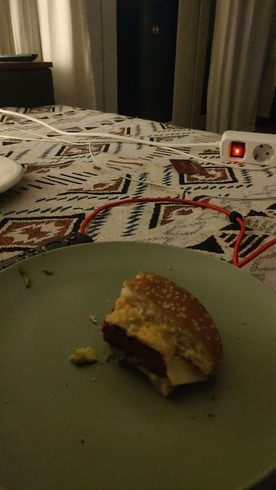 Photo of a homemade burger on a wooden serving board with fries in the background.