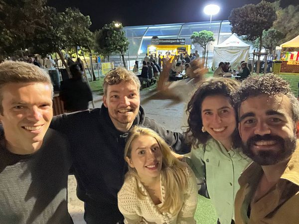 A group of five friends poses together at night during the Beerceira festival.