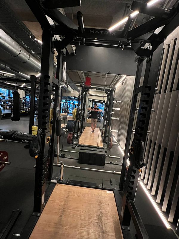 A gym interior featuring a squat rack and various workout equipment.