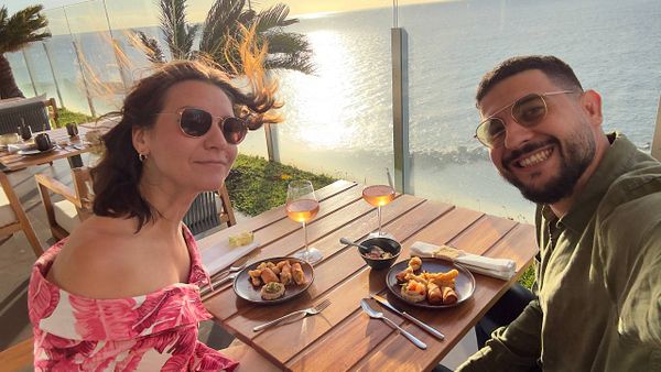 A couple enjoys a celebratory meal by the seaside during sunset.