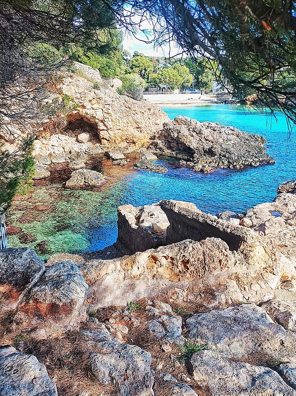 A scenic coastal view featuring clear turquoise water and rocky formations.