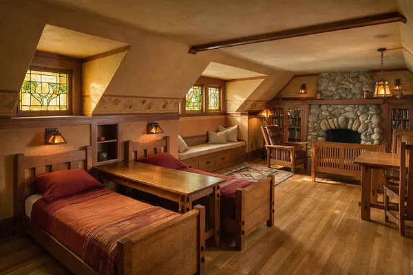 A warm Craftsman-style kids' room with two wooden twin beds, a built-in window seat, and a large stone fireplace at the far end. Stained glass windows, wood trim, soft amber lighting, and earthy textiles create a cozy, rustic atmosphere.