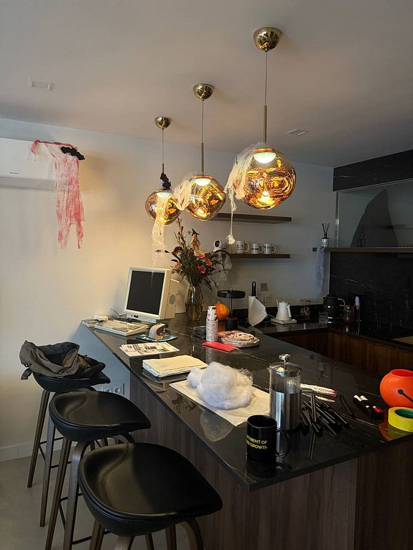 A modern kitchen decorated for a Halloween BBQ party with various festive elements.