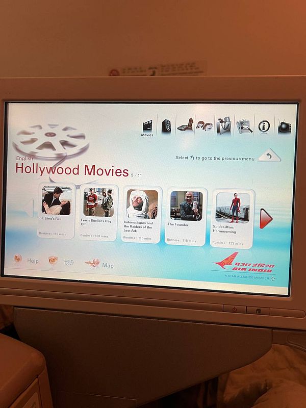 The image displays an in-flight entertainment screen featuring a selection of Hollywood movies.
