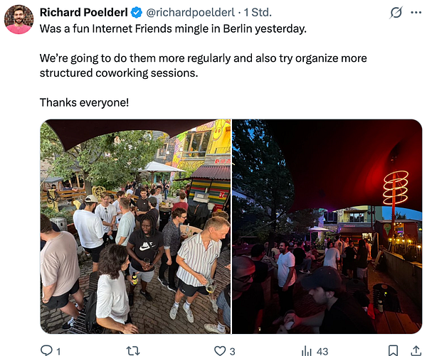 A group photo of about 30 people gathered outdoors in front of a building for a meetup.