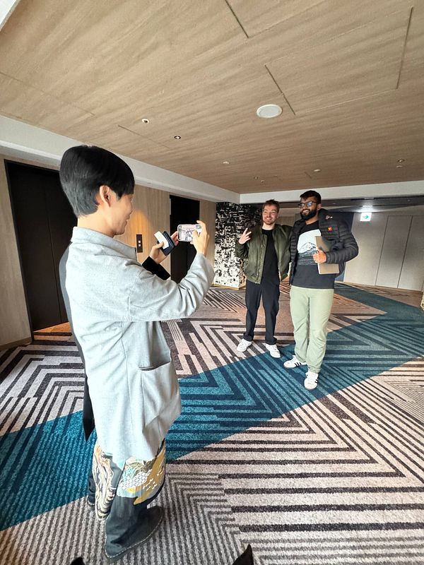 Three individuals are posing for a photo in a modern indoor setting.
