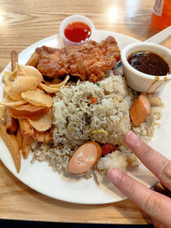 A vibrant food platter featuring a variety of Malaysian dishes presented in white bowls and a plate on a wooden surface.