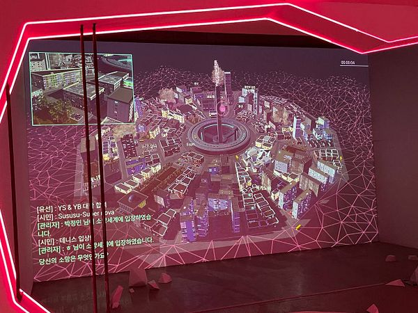 A digital art installation featuring a 3D model of a cityscape projected on a wall.