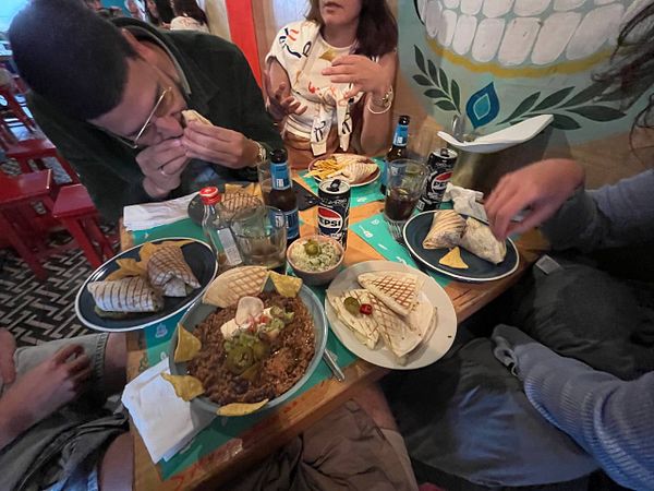 A group of friends enjoying a meal at a vibrant restaurant with various dishes on the table.