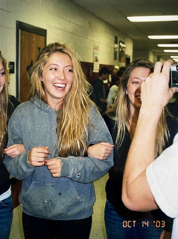 A group of young women are smiling and posing for a photo in a school hallway.