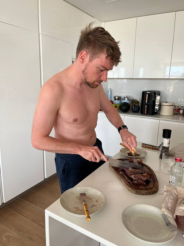A man is preparing steak in a modern kitchen.