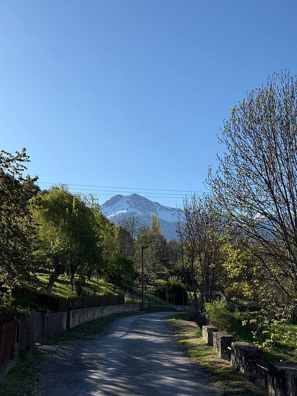 Scenic mountainous landscape with an empty two-lane road, in Hautes-Alpes, France under a cloudy sky.