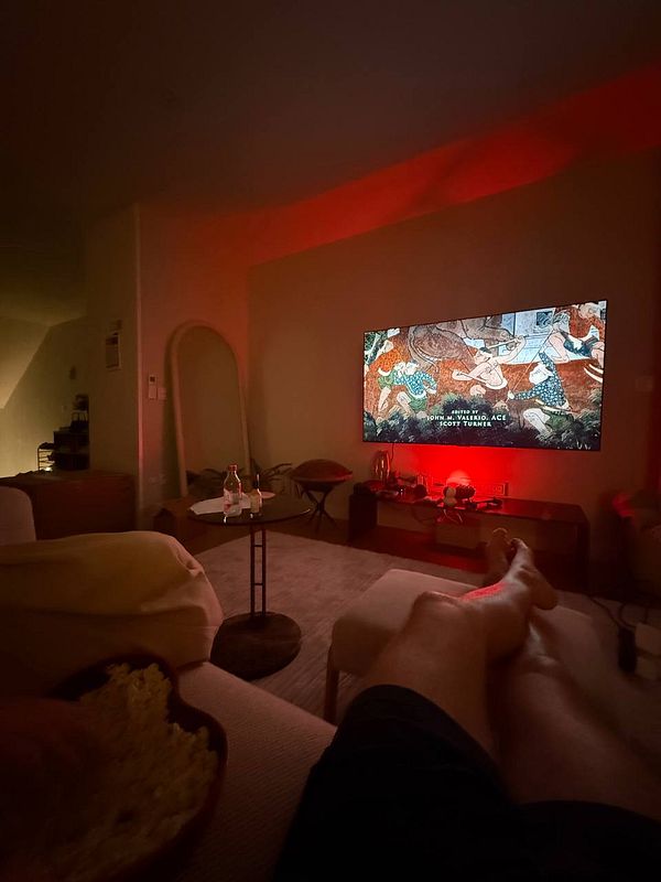 A cozy living room scene featuring a person relaxing while watching a show on a large TV.