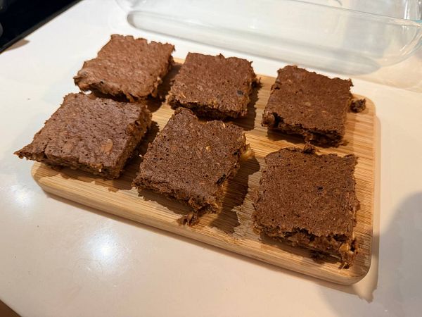 A plate of homemade brownie banana pancakes topped with banana slices and syrup on a kitchen countertop.