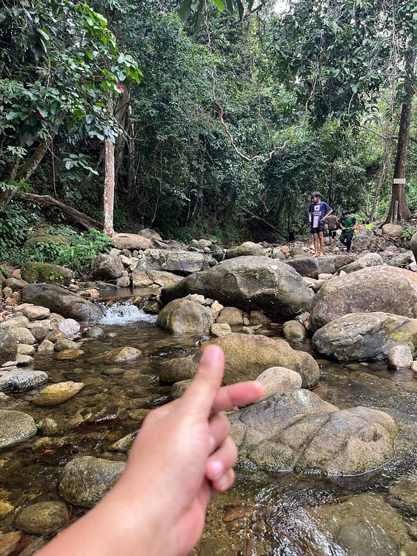 A scenic river landscape with a person gesturing in the foreground and others exploring in the background.