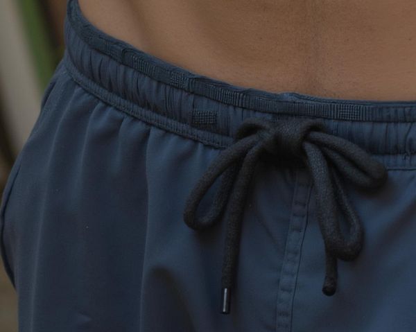 A close-up view of a person's waist wearing dark blue shorts with a drawstring.