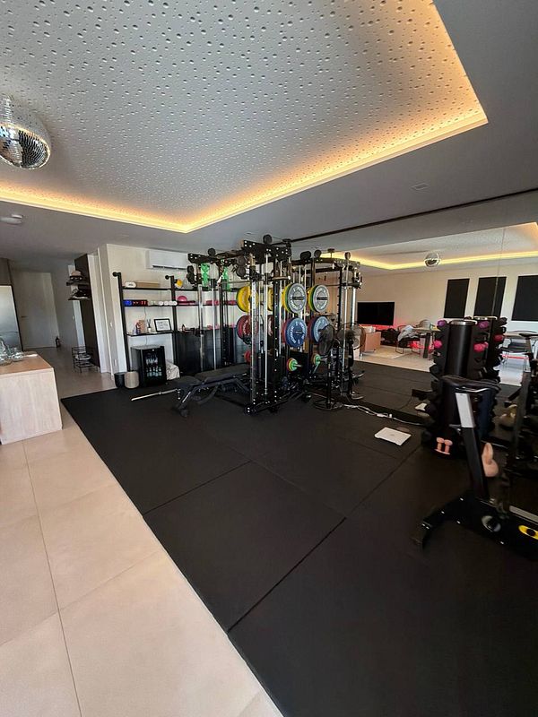Photo of a man lifting weights in a gym with various exercise equipment around.