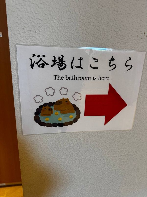 A sign indicating the location of the bathroom in a playful manner.