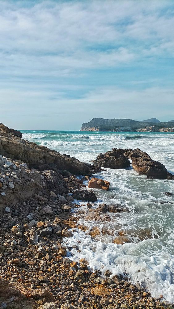 A person walking alone on a wet, deserted street during a stormy day with an umbrella and city buildings in the background.
