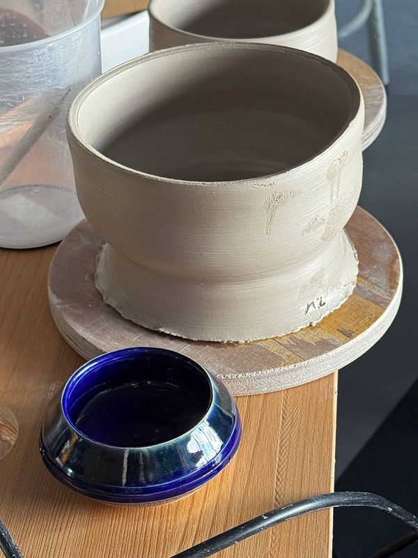 A person throwing clay on a pottery wheel.
