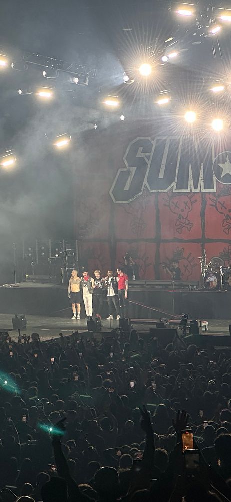 A crowd gathers to witness the final concert of Sum 41, featuring the band on stage.