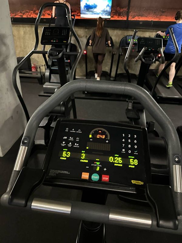 The image captures a gym setting featuring exercise equipment and individuals working out.