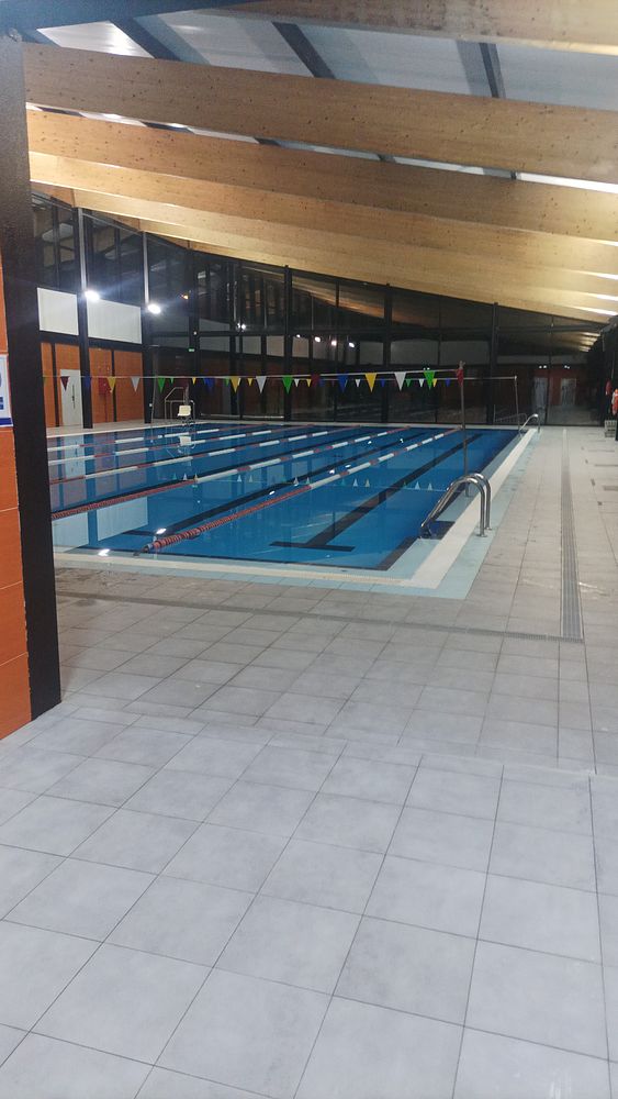 An indoor swimming pool with multiple lanes and a modern architectural design.