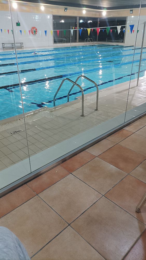 An indoor swimming pool is visible, featuring clear water and colorful flags along the edges.