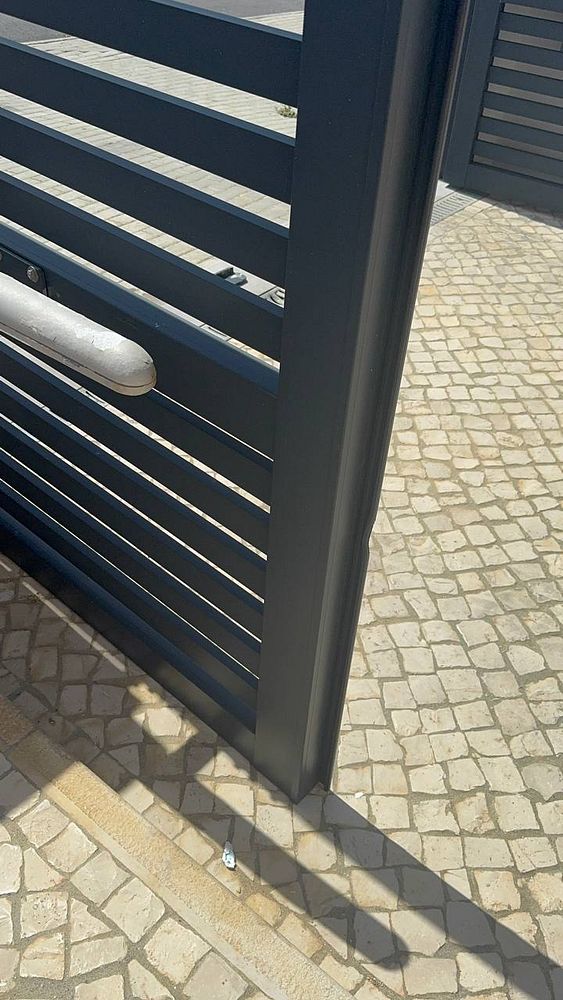 The image depicts a damaged electric gate that is unable to move due to contact with the ground.