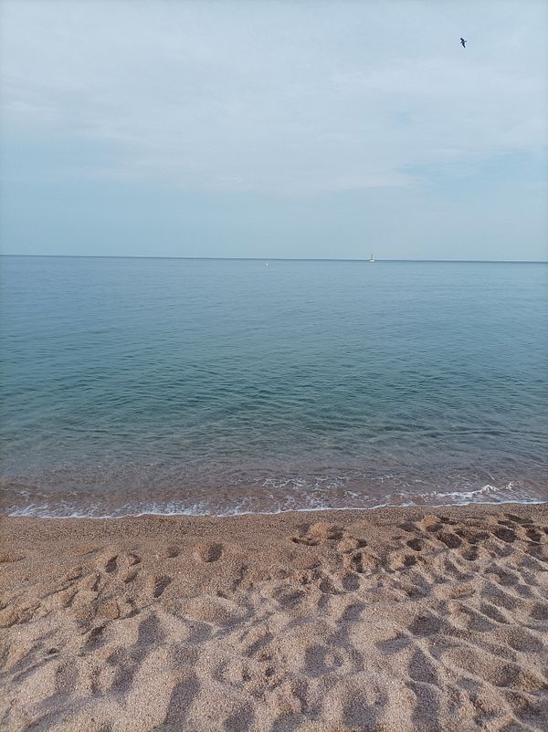 A serene beach scene at Sant Pol de Mar with calm waters and a sandy shore.