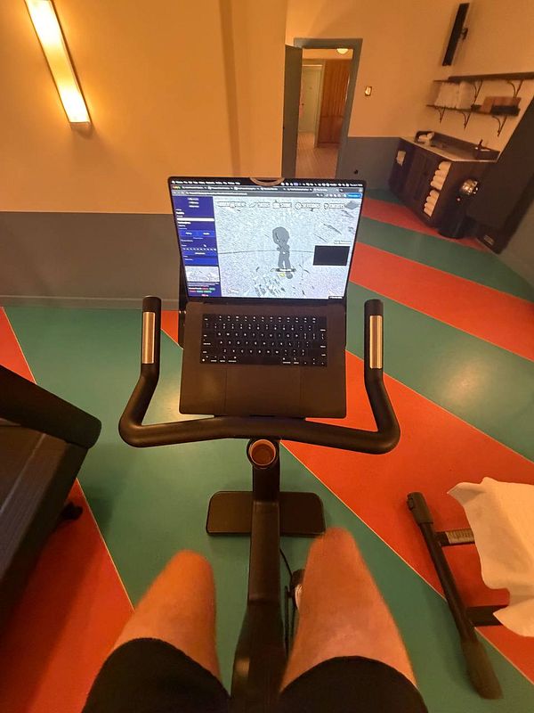 A woman is exercising on a stair stepper machine in a gym filled with various fitness equipment.