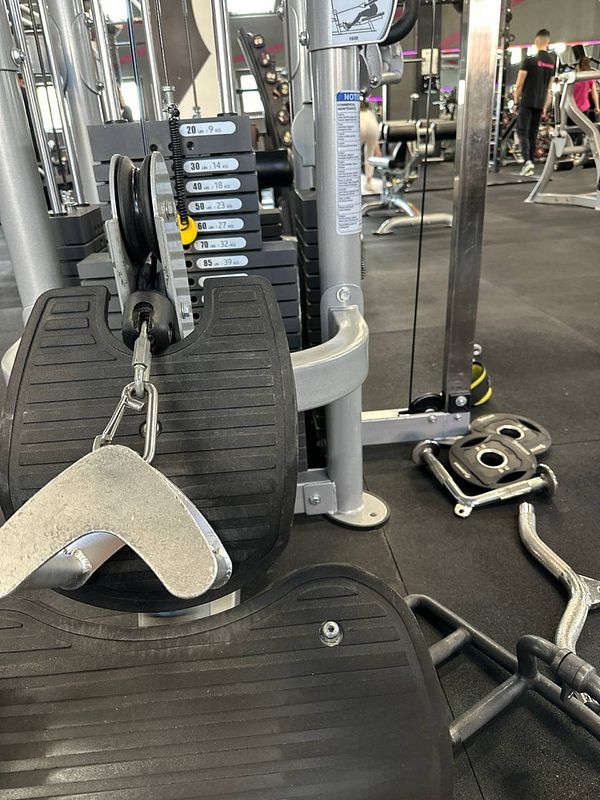 The image captures a close-up view of gym equipment, specifically a cable machine with weights and attachments.