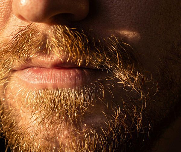 A close-up image of a man's mouth and beard, highlighting the texture and color of the facial hair.