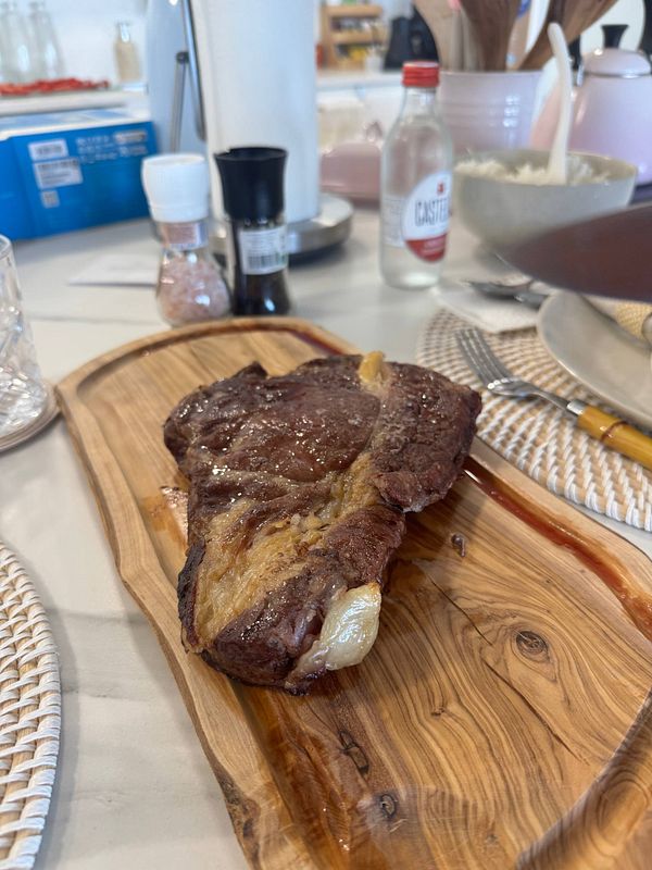A beautifully cooked steak is presented on a wooden serving board.