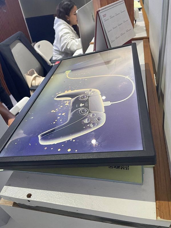 A photo of a PlayStation 5 console in a repair shop setting with tools and shelves in the background.