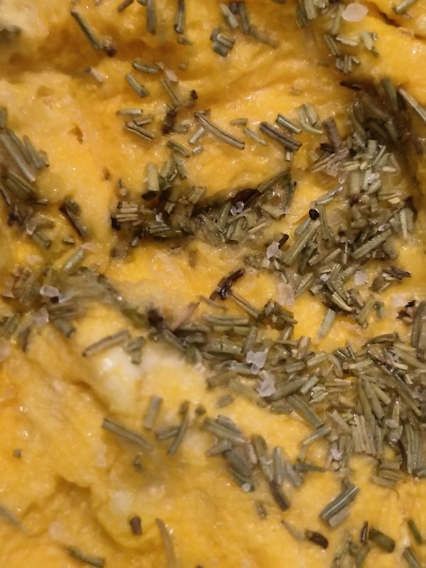 A close-up view of scrambled eggs garnished with herbs.