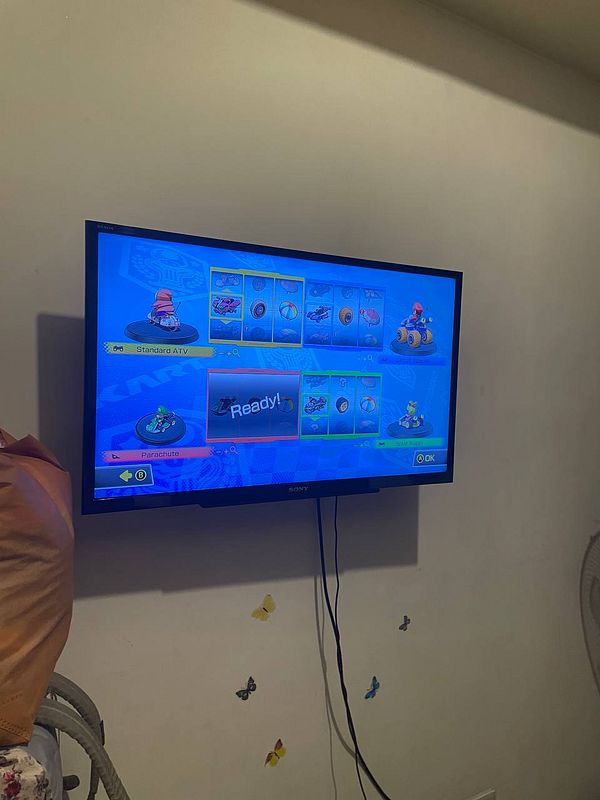 A gaming setup displaying a Mario Kart selection screen on a TV.