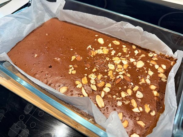Close-up view of several freshly baked chocolate brownies on parchment paper in a pan.