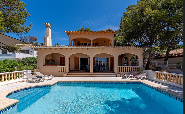 A beautiful villa with a swimming pool surrounded by lush greenery.