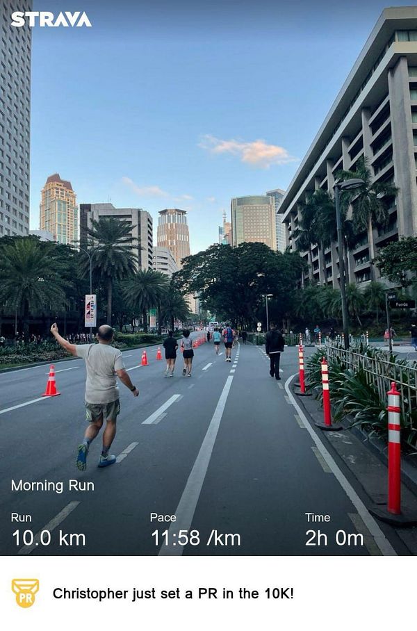 A runner celebrates completing a 10km run in an urban setting.