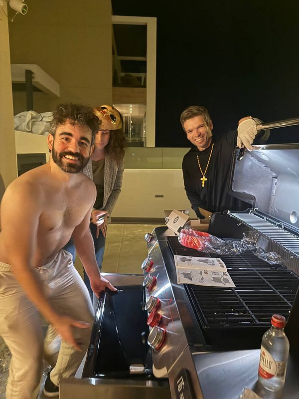 A group of three friends prepares for a Halloween BBQ party at night.