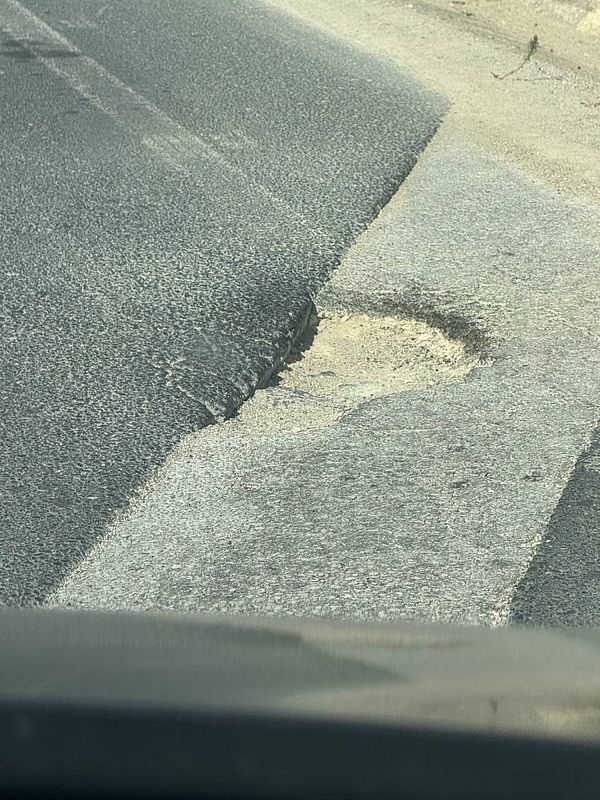 A large pothole is visible on a road, posing a potential hazard for vehicles.