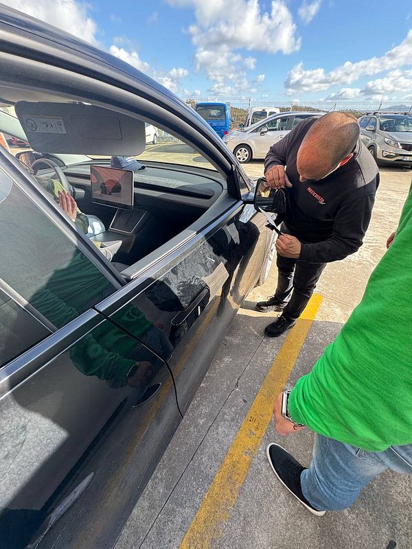 A mechanic is assisting a customer with a car issue in a parking lot.